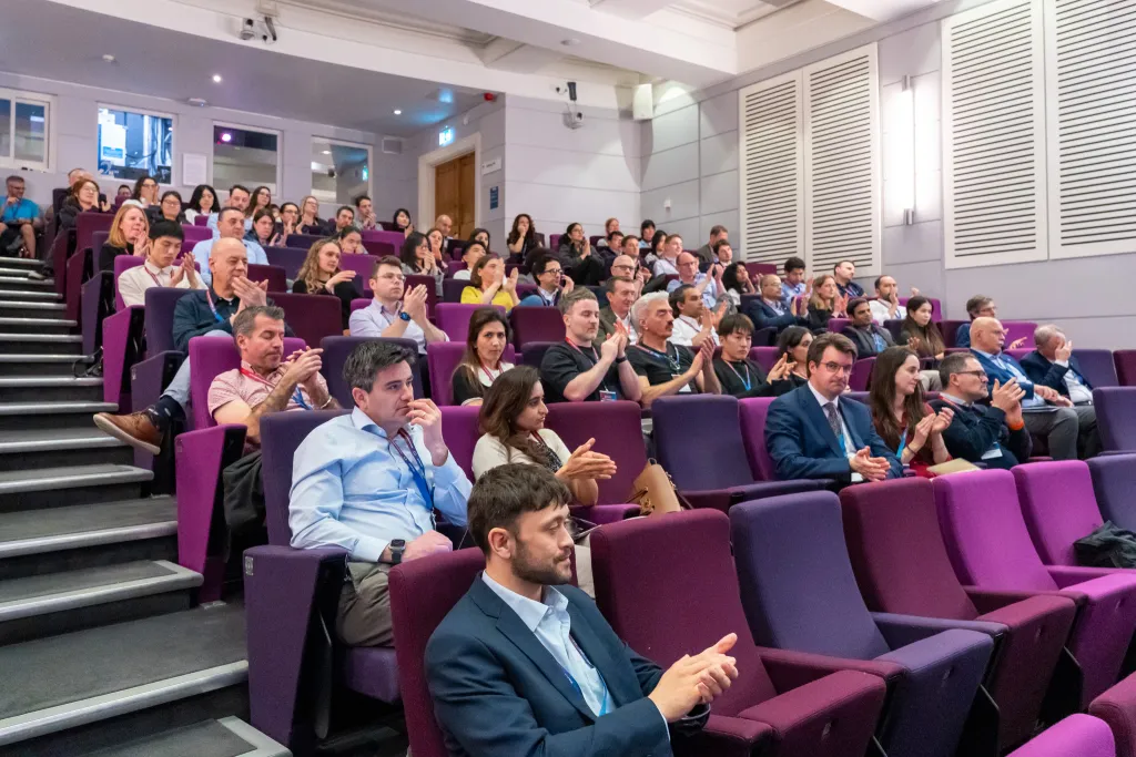 Symposium participants clapping while seated in auditorium.